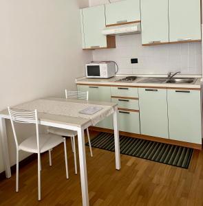 cocina blanca con mesa y microondas en La Terrazza del Centro, en Bérgamo