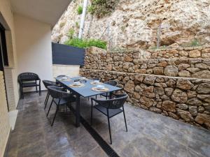 a table and chairs on a patio with a stone wall at Casa Buena Vista con piscina y ascensor in Cullera