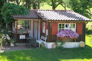 a small red shed with a table and flowers at Zum Torfstecher in Wilhelmsdorf