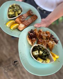 a person holding two plates with different types of food at Apartmani Konoba Starčevo in Virpazar