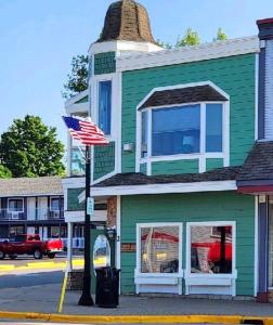 a green building with an american flag on a street at Pier Harbor #1 & #2 in Saint Ignace