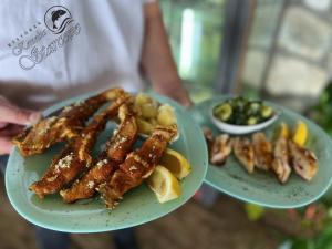 a person holding two plates with food on them at Apartmani Konoba Starčevo in Virpazar