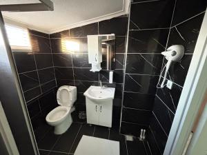 a black tiled bathroom with a toilet and a sink at NAVAL HOTEL YALOVA in Yalova