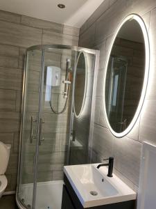 bagno con doccia, lavandino e specchio di Walter Road Holiday Home Swansea - 4 bedrooms a Swansea