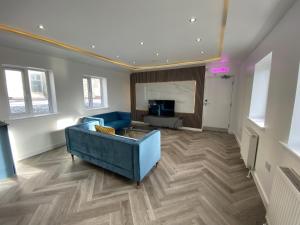 un salon avec un canapé bleu et une télévision dans l'établissement Walter Road Holiday Home Swansea - 4 bedrooms, à Swansea