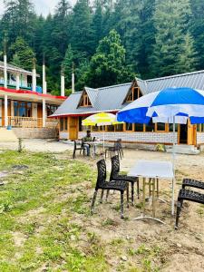 a group of chairs and tables with umbrellas in front of a building at Secrets of Parvati in Kalgha