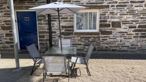 a table and chairs with an umbrella in front of a building at The Forge, Elegant Luxury Apartment with Bike store - Sleeps 4 in Wick
