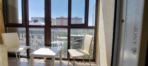einen Balkon mit 2 Stühlen und einem Tisch vor einem Fenster in der Unterkunft Apartment with panoramic view in the center in Bischkek