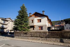 アルプにあるCasa amb jardí Alpの木の横の石垣上の家