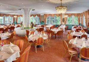 a restaurant with tables and chairs and a chandelier at Ensana Butterfly in Mariánské Lázně