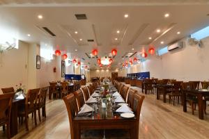 HOTEL ANAND INTERNATIONAL في بود جايا: غرفة طعام بها طاولات وكراسي ومصابيح حمراء