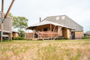 een houten huis met een veranda en een dak bij Glamping Callantsoog in Callantsoog