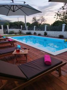 a large swimming pool with tables and an umbrella at Apartment Karla SNB in Lozovac