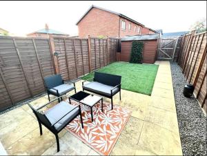 a patio with three chairs and a table and a lawn at Broad Acre House - Nr Racecourse in Cheltenham