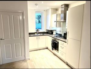 a kitchen with white cabinets and a white door at Broad Acre House - Nr Racecourse in Cheltenham
