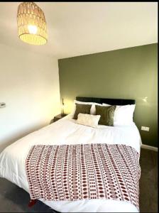 - une chambre avec un grand lit blanc et un mur vert dans l'établissement Broad Acre House - Nr Racecourse, à Cheltenham