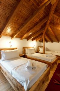 two beds in a room with wooden ceilings at Hotel Sarajet 1821 in Gjirokastër