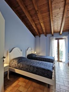two beds in a bedroom with blue walls and wooden ceilings at Luci nel Bosco 