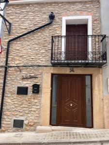 ein Gebäude mit einer Holztür und einem Balkon in der Unterkunft Ca la Beata in Cálig