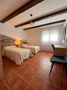 een slaapkamer met 2 bedden en een stoel. bij Ca la Beata in Cálig