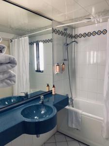 ein Badezimmer mit einem blauen Waschbecken und einer Badewanne in der Unterkunft Mercure Besancon Parc Micaud - Hotel & Bar in Besançon