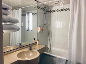 ein Badezimmer mit einem Waschbecken, einem Spiegel und einer Badewanne in der Unterkunft Mercure Besancon Parc Micaud - Hotel & Bar in Besançon