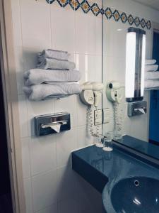 ein Badezimmer mit einem Waschbecken, einem Spiegel und Handtüchern in der Unterkunft Mercure Besancon Parc Micaud - Hotel & Bar in Besançon