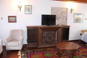 a living room with a tv and a chair at Cunda adasında rum evi in Ayvalık
