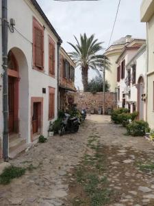 un callejón entre dos edificios con una palmera en Cunda adasında rum evi, en Ayvalık