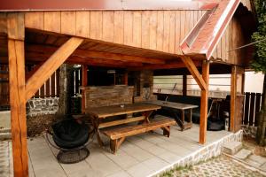 a wooden pavilion with a picnic table and benches at Cabana Hai la munte! in Muntele Băişorii