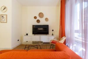 een woonkamer met een oranje bank en een tv bij Sonnino House in Cagliari