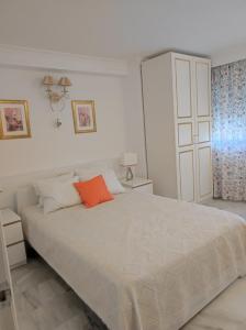 1 dormitorio con 1 cama blanca grande con almohada naranja en Apartamento El Coloso 4Q, en Benalmádena