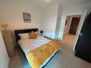 a bedroom with a bed with a gold blanket on it at Stylish 3 beds North Greenwich 02 Arena Apartment in London