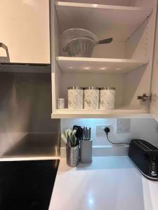 a kitchen counter with cups and utensils on a shelf at Stylish 3 beds North Greenwich 02 Arena Apartment in London