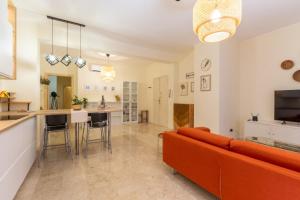 een woonkamer met een oranje bank en een keuken bij Sonnino House in Cagliari
