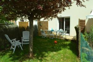 un cortile con tavolo e sedie sotto un albero di Maison St Eloi by iZiLi *Futuroscope*Jardin* a Poitiers