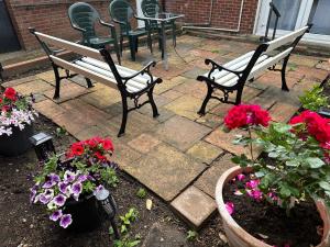 zwei Bänke und Blumen auf einer Terrasse mit einem Tisch und Stühlen in der Unterkunft 116 Maison Dieu Road Room A in Dover in Dover