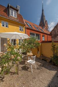 einen Hof mit einem Stuhl und einem Regenschirm vor einem Haus in der Unterkunft Luettje Huus in Flensburg