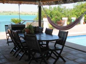 a table with chairs and a hammock on a patio at Espectacular casa con embarcadero. in Arcos de la Frontera