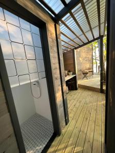 eine Glastür zu einer Dusche auf einer Holzterrasse in der Unterkunft DuneHouse in Tūja