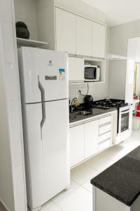 eine weiße Küche mit Kühlschrank und Herd in der Unterkunft Itanhaém Praia & Mar in Itanhaém