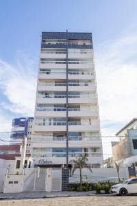 ein hohes Gebäude mit einem davor geparkt in der Unterkunft Itanhaém Praia & Mar in Itanhaém