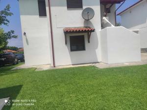a white house with a window and green grass at Mary's House in Vourvourou