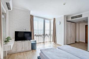 a bedroom with a flat screen tv and a large window at Aparthotel Royal Marina Beach in Chernomorets