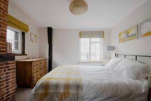 a bedroom with a bed and a dresser and two windows at Characterful apartment in the heart of Petworth in Petworth
