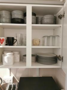 116 maison dieu Road room B in Dover في دوفر: خزانة بيضاء مليئة بالأطباق والأطباق
