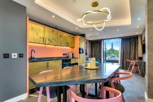 a kitchen with a wooden table and pink chairs at Roomzzz Edinburgh in Edinburgh