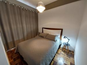 um quarto com uma cama e um candeeiro sobre uma mesa em Próximo dos melhores hotéis do centro, 2 quartos, portaria 24h em Florianópolis