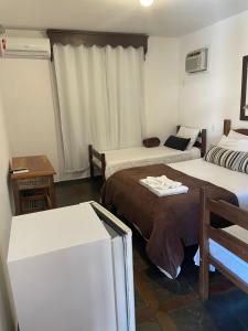 a hotel room with two beds and a refrigerator at Pousada Minas Goiás in Tiradentes