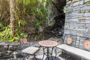 eine Terrasse mit einem Tisch, Stühlen und einer Steinmauer in der Unterkunft Casa Magging un oasi nel verde in Locarno